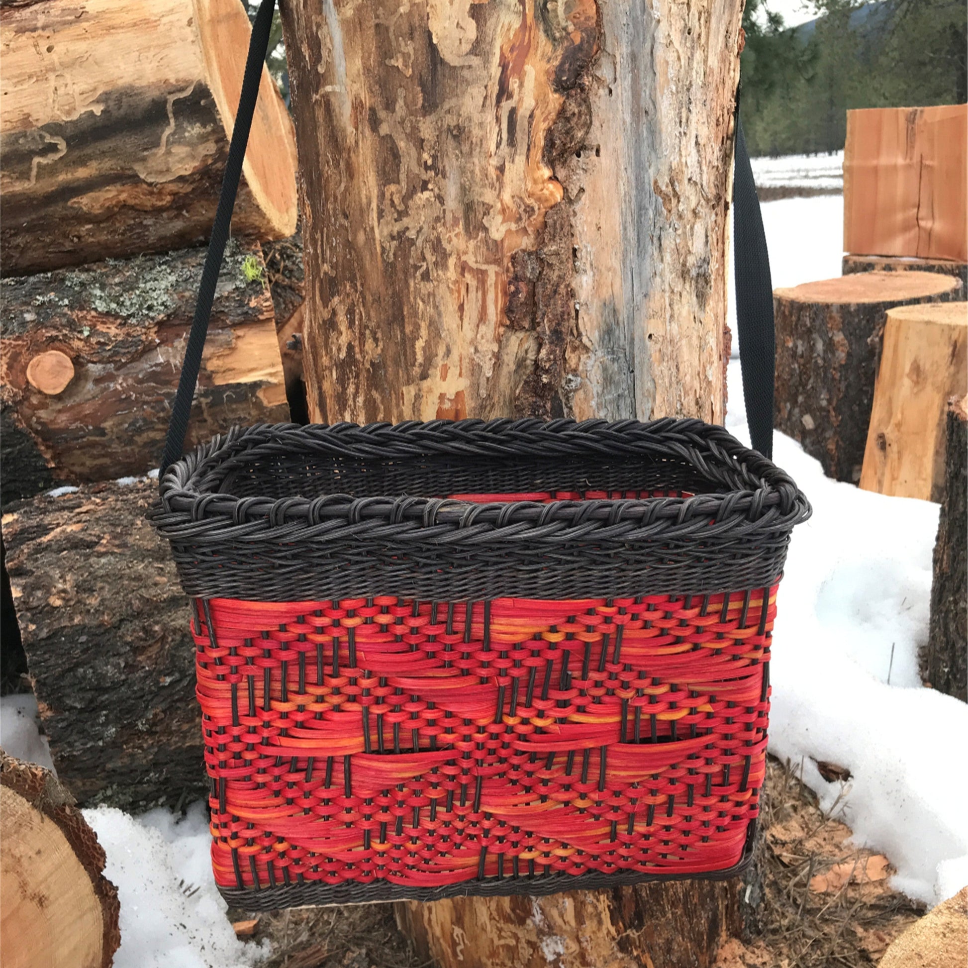 This eye-catching basket features a vibrant design with bold red and black patterns, showcasing intricate weaving techniques. The rectangular shape and sturdy black handle make it practical for carrying or hanging, adding a functional element to its artistic appeal. The combination of colors and textures makes it a striking piece, perfect for storage or display. Ideal for crafters interested in basket kits and basket materials, this basket highlights the beauty of fiber art and basketry